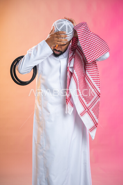 الاستعداد للخروج, التزين و التجمل و الترتيب, شاب سعودي عربي خليجي يرتدي الثوب و الشماغ الأحمر, الاهتمام بالمظهر الخارجي و الشياكه و  الأناقة, خطوات لبس الشماغ السعودي التقليدي, خلفية ملونة.