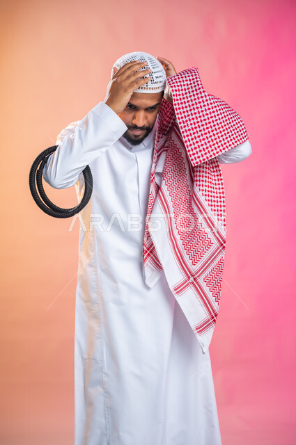 الاستعداد للخروج, التزين و التجمل و الترتيب, شاب سعودي عربي خليجي يرتدي الثوب و الشماغ الأحمر, الاهتمام بالمظهر الخارجي و الشياكه و  الأناقة, خطوات لبس الشماغ السعودي التقليدي, خلفية ملونة.