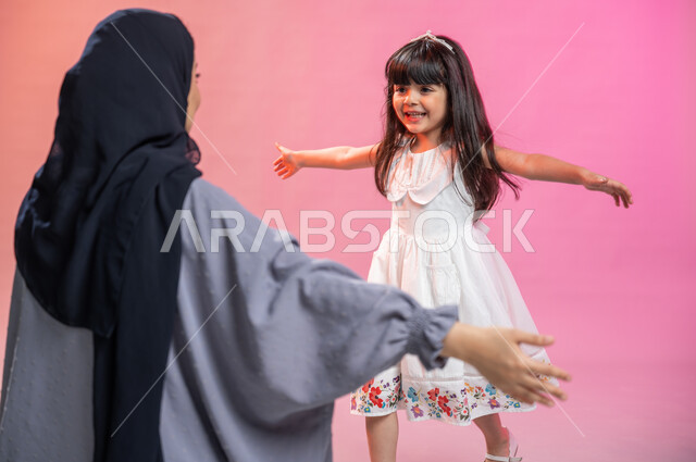 ايماءات طفلة تدل على الاشتياق و الحب, مشاعر الأمومة و العطف، بورتريه لفتاة عربية خليجية سعودية تركض بتلهف لتعانق والدتها, عناق الأبناء،  مفهوم الأسرة السعيدة ، قضاء أوقات عائلية ممتعة, خلفية ملونة.