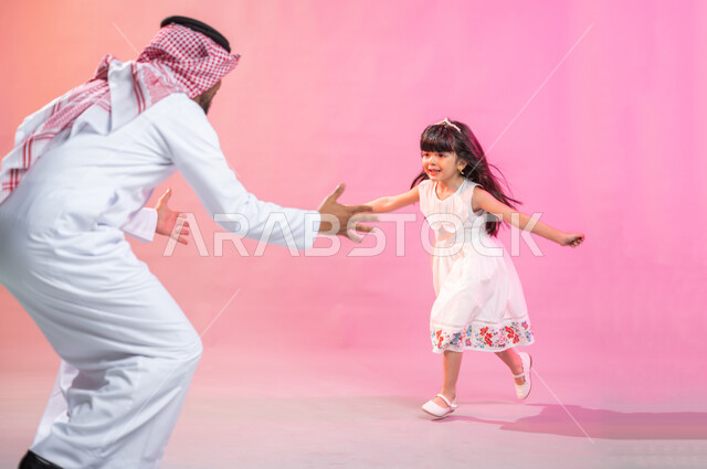 Feelings of paternity and affection, gestures of a child indicating longing and love, spending enjoyable family times, a portrait of a Saudi Arabian Gulf girl running eagerly to hug her father, children hugging, the concept of a happy family, a colored ba