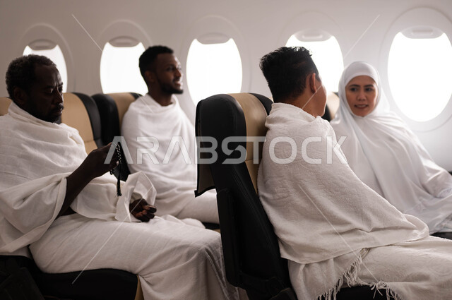 مجموعة من الحجاج يرتدون ملابس الاحرام ويجلسون في الطائرة، الاستعداد للذهاب الى الحج، فضل العمرة في شهر رمضان، السفر الى مكة لآداء مناسك الحج والعمرة، موسم الحج 2023، استقبال الحجاج من خارج السعوديه، خطوط الطيران السعودي