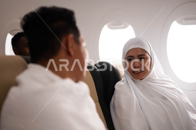 الاستعداد للذهاب للحج، زوجان اندونيسيان ملسمان يرتديان ملابس الاحرام ويجلسان في الطائرة، موسم الحج 2023، السفر الى مكة لآداء مناسك الحج والعمرة، فضل العمرة في شهر رمضان، خطوط الطيران السعودي