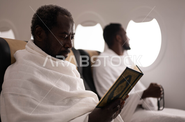 التسبيح والاستغفار وذكر الله تعالى، حفظ وتفسير القران الكريم، رجلان عربيان من السودان يرتديان ملابس الاحرام ويجلسان في الطائرة، قراءة وتلاوة القران، السفر الى مكة لآداء مناسك الحج والعمرة، موسم الحج 2023، آداء العمرة في رمضان، خطوط الطيران السعودي