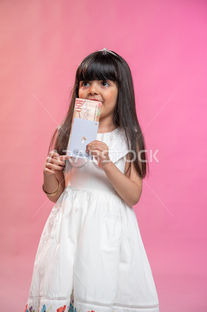 Obtaining an Eidiya on the occasion of happy holidays, facial gestures indicating happiness and pleasure, a portrait of a Saudi Arabian Gulf girl holding money in her hand, congratulations on the advent of the Eid, Islamic holidays and occasions, a colorf