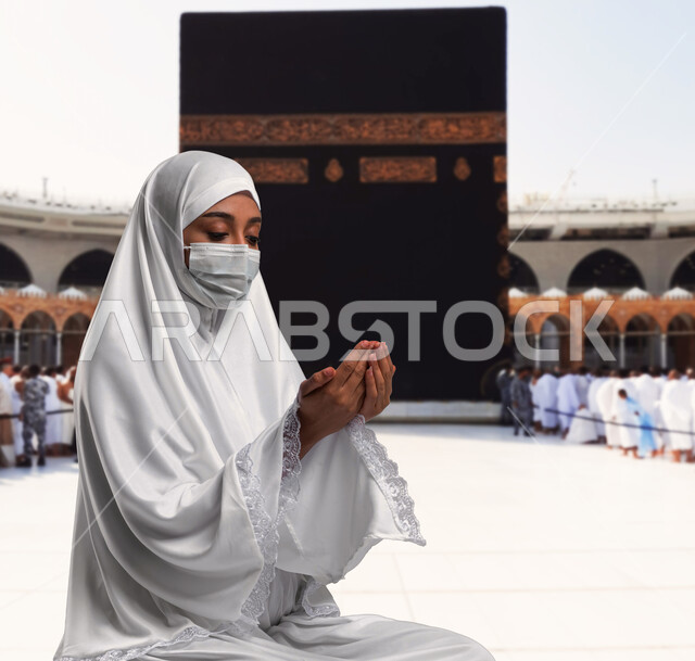 ايماءات يدين تدل على الدعاء بتضرع و خشوع, أداء فريضة الحج و العمرة في موسم الحج 2023, إمرأة ترتدي لباس الإحرام وتجلس في بيت الله الحرام في مكه المكرمه,الالتزام بالإجراءات الاحترازية للوقاية من الأمراض, خلفية الحرم النبوي الشريف.