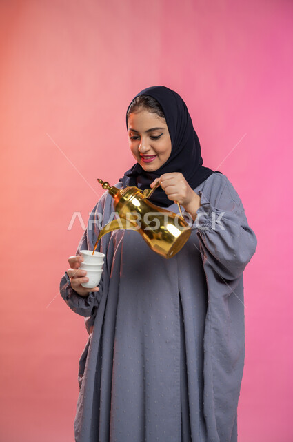 تقديم القهوة العربية في الأعياد والمناسبات ، بورتريه لسيدة عربية سعودية خليجية محجبة ترتدي العباءه الخليجية تقوم بصب فنجان قهوة ساخن، حسن الضيافة والاستقبال وإكرام الضيوف، خلفية ملونة