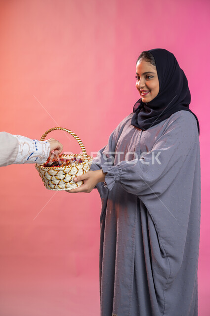 إيماءات تدل على الفرح والسعادة، أجواء العائلة السعودية في العيد، بورتريه لامرأة خليجية عربية سعودية تقدم حلوى العيد، اكرام الضيف، حسن الضيافة والاستقبال و الترحيب بالضيوف، عادات في المجتمع السعودي في الأعياد،  احتفالات ومناسبات إسلامية، خلفية ملونة. 