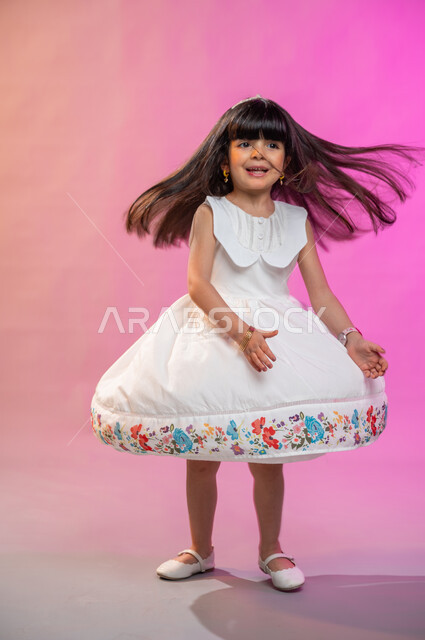  إيماءات وجه تدل على الفرح والبهجة والسرور، فرحة الأطفال بثياب العيد الجديدة ، بورتريه لطفلة عربية سعودية خليجية ترتدي فستان جميل، صورة الجسم بالطول الكامل، خلفية ملونة