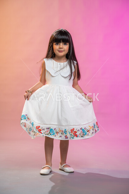  إيماءات وجه تدل على الفرح والبهجة والسرور، فرحة الأطفال بثياب العيد الجديدة ، بورتريه لطفلة عربية سعودية خليجية ترتدي فستان جميل، صورة الجسم بالطول الكامل، خلفية ملونة