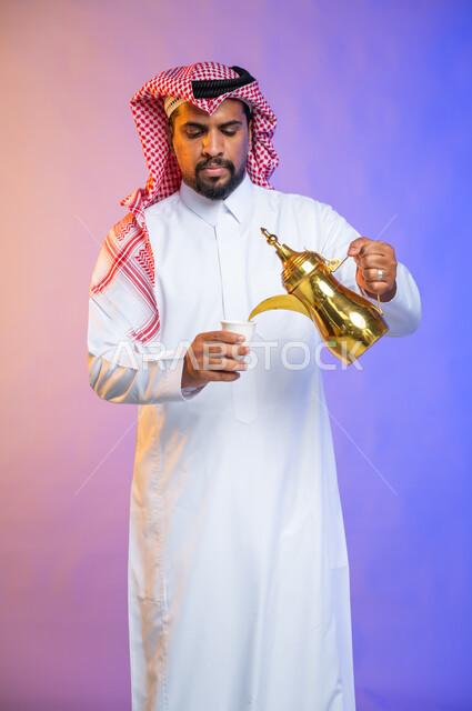 إيماءات وجه تدل على البشاشه والترحيب بالضيوف, إكرام الضيف و حسن الضيافه والاستقبال, بورتريه لرجل عربي سعودي خليجي يرتدي الثوب والشماغ السعودي التقليدي يحمل بيده دلة القهوه العربيه, منتج وطني سعودي محلي، أعياد ومناسبات إسلامية سعيدة، خلفية ملونة