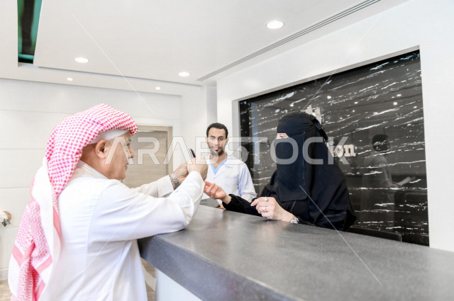 A Saudi Arabian Gulf man at the hospital reception, fills in his data at the receptionist, completes admission procedures to the hospital, provides health care