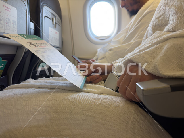 ورقة تعليمات و ارشادات السلامه في حالة الطواريء, مفهوم السفر الآمن والحفاظ على سلامة الركاب, صورة مقربة  لرجل عربي خليجي سعودي يرتدي ملابس الاحرام , رحلات جوية اسلامية دينية سياحية .