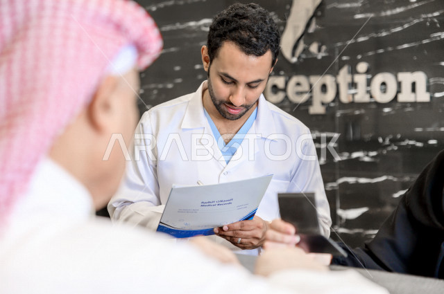 A Saudi Arabian Gulf man at the hospital reception, fills in his data at the receptionist, completes admission procedures to the hospital, provides health care