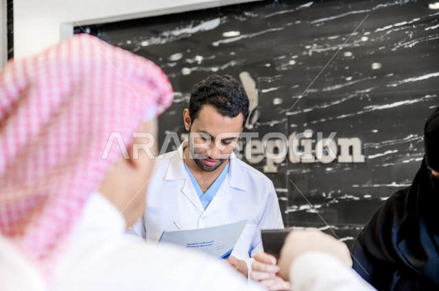 A Saudi Arabian Gulf man at the hospital reception, fills in his data at the receptionist, completes admission procedures to the hospital, provides health care