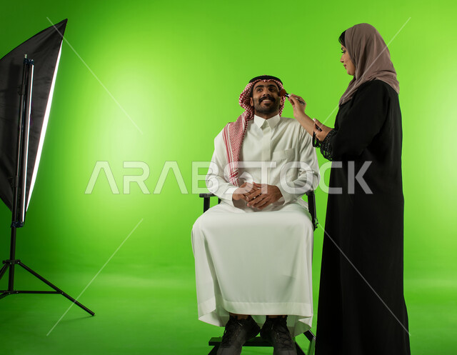 كروما لجلسة تصوير في الاستوديو، امرأة عربية سعودية خليجية تقوم بتحضير وتجميل العارض للصور الفوتوغرافية، الاستعداد لجلسة التصوير، خلفية شاشة خضراء، خلف الكواليس