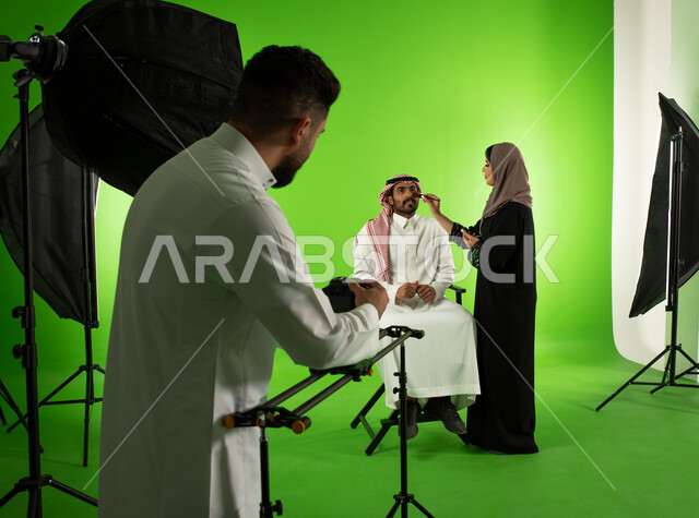 تجميل وتحضير العارض للصور الفوتوغرافية، كروما لجلسة تصوير في الاستوديو، مصور محترف عربي سعودي خليجي يقوم بتجهيز الكاميرا الالكترونية الحديثة، الاستعداد لجلسة التصوير، خلفية شاشة خضراء، خلف الكواليس