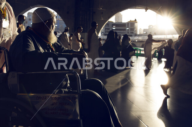 التقرب الى الله تعالى بالاعمال الصالحه ، صورة لرجل عربي سعودي خليجي يقوم بمساعدة والده على آداء مناسك الحج والعمره ، مفهوم بر الوالدين  ومساعدة كبار السن وذوي الاحتياجات الخاصه ، موسم الحج2023.