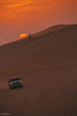 Sunset view in the desert of Saudi Arabia, a Jeep Grand Cherokee tour in the desert, golden sand dunes, a Saudi Arabian Gulf man sitting on the soft sand, nature background