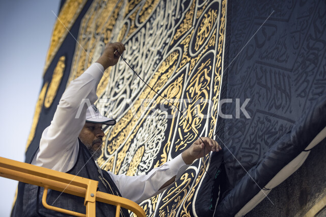 عامل يقف على الرافعة و يخيط كسوة قبلة المسلمين, تغيير ثوب الكعبة المشرفة القديم بثوب جديد, استبدال كسوة الكعبة المشرفة بعد فجر التاسع من شهر ذي الحجة, أداء مناسك الحج, موسم الحج 2023.