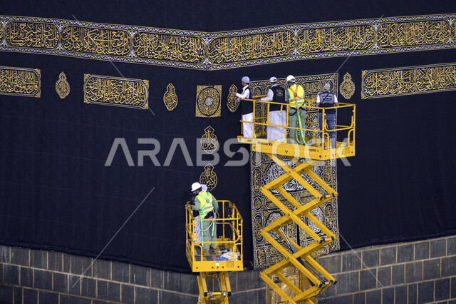 عمال يقفون على الرافعات لتبديل كسوة قبلة المسلمين, استبدال كسوة الكعبة المشرفة بعد فجر التاسع من شهر ذي الحجة, تغيير ثوب الكعبة المشرفة القديم بثوب جديد, أداء مناسك الحج, موسم الحج 2023.