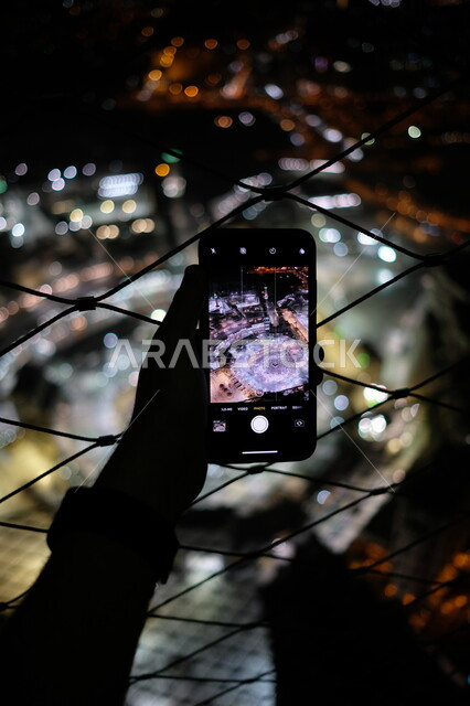 صورة ظلية ليد رجل يمسك الهاتف المحمول ويقوم بتصوير مناسك الحج، التقاط صور تذكارية، حجاج بيت الله الحرام يطوفون حول الكعبة، موسم الحج 2023