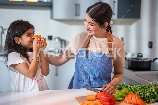 مفهوم النظام الغذائي، فنون الطبخ والتقطيع, ايماءات تدل على السعادة, أم عربية خليجية سعودية تقوم بتعليم ابنتها الطبخ، غذاء صحي ومفيد، سلطة الخضار الطازجة اللذيذة، إعداد و تحضير الطعام، وصفات الطعام الشهية, قضاء أوقات ممتعة مع الأبناء