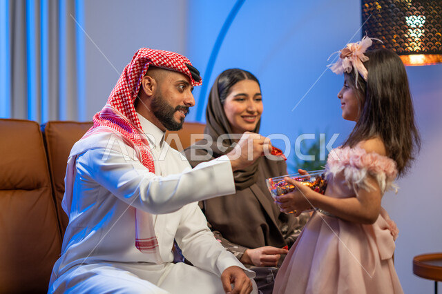 أجواء العيد في المجتمع العربي السعودي, فتاة عربية خليجية سعودية تقوم بتقديم قطع الشوكولاتة في مناسبة العيد السعيد, تجمع أسري لعائلة عربية خليجية سعودية في غرفة الجلوس ,حسن استقبال واكرام الضيوف, مناسبات و أعياد إسلامية