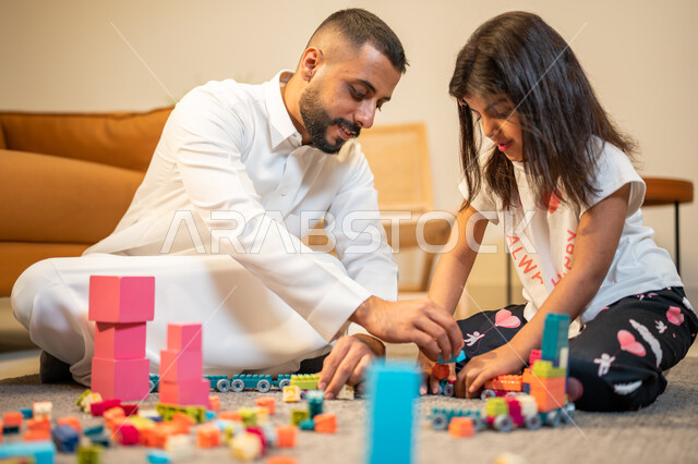 رعاية وتشجيع و تطوير مهارات الأطفال، اب عربي خليجي سعودي يشارك ابنته اللعب، انشطة ترفيهية للابناء، الاستمتاع واللعب بالمكعبات، الجلوس في غرفة المعيشة، الاهتمام ودعم الأبناء، قضاء اوقات عائلية ممتعة