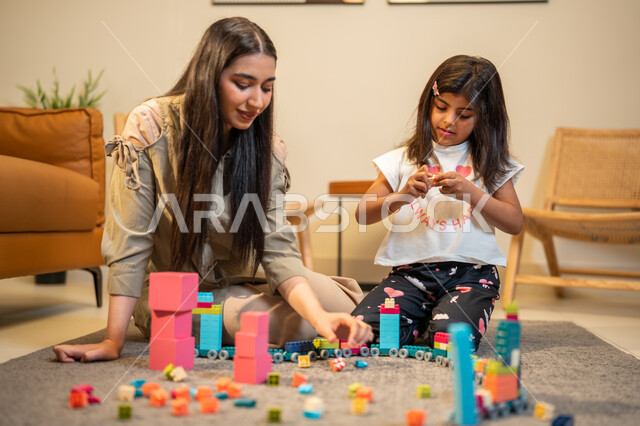 الاستمتاع بتركيب المكعبات، ام عربية خليجية سعودية تلعب مع ابنتها، ايماءات وجه تدل على السعادة، مفهوم الأمومة والطفولة، رعاية وتشجيع وتطوير مهارات الأطفال، الاهتمام بالأبناء ودعمهم، قضاء اوقات عائلية ممتعة