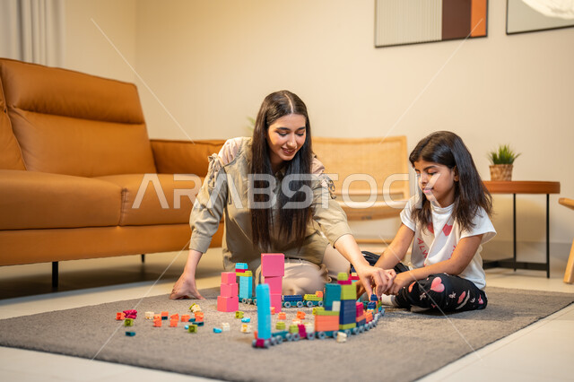 رعاية وتشجيع وتطوير مهارات الأطفال، ام عربية خليجية سعودية تلعب مع ابنتها، الاستمتاع بتركيب المكعبات، ايماءات وجه تدل على السعادة، مفهوم الأمومة والطفولة، الاهتمام بالأبناء ودعمهم، قضاء اوقات عائلية ممتعة