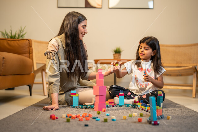 رعاية وتشجيع وتطوير مهارات الأطفال، ام عربية خليجية سعودية تلعب مع ابنتها، الاستمتاع بتركيب المكعبات، ايماءات وجه تدل على السعادة، مفهوم الأمومة والطفولة، الاهتمام بالأبناء ودعمهم، قضاء اوقات عائلية ممتعة