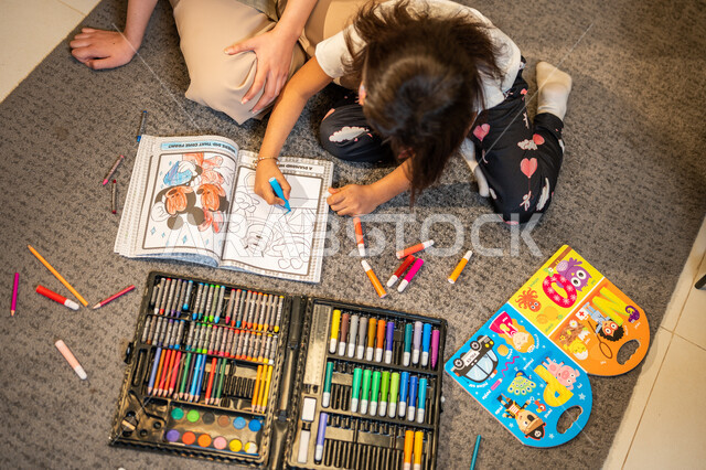 A bag of coloring tools and equipment, creative artistic activities, a Saudi Arabian Gulf mother who teaches and shares her daughter with coloring, the concept of motherhood and childhood, care, encouragement and development of children's skills, spending