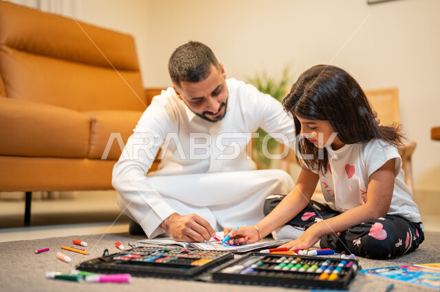 Coloring tools and equipment, a Saudi Arabian Gulf father who teaches and shares his daughter with coloring, care, encouragement and development of children's skills, learning, creativity and skills development, a game of coloring drawings, spending fun f