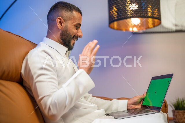 استخدام  جهاز الحاسوب المحمول بخلفية خضراء كروما، رجل عربي خليجي سعودي يجلس في غرفة المعيشة ،ايماءات تدل على التحية والسلام, إجراء مكالمة فيديو، التسويق لموقع إلكتروني، مشاهدة الأفلام والمسلسلات