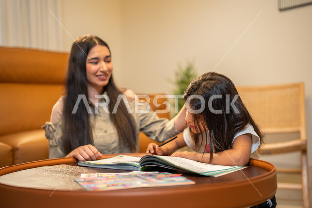 ام عربية سعودية خليجية تقوم بتعليم ابنتها، مساعدة الابناء في تأدية الواجبات المدرسية، الانشطة التعليمية وتنمة القدرات، تعلم وتطوير الابناء، الاهتمام بتعليم بالأبناء ودعمهم