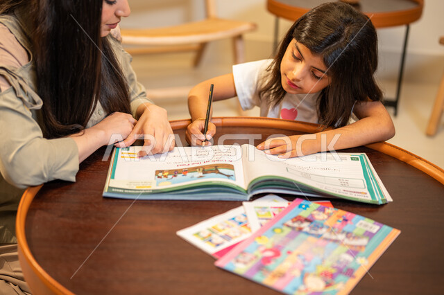 الاهتمام بتعليم بالأبناء ودعمهم، ام عربية سعودية خليجية تقوم بتعليم ابنتها، مساعدة الابناء في تأدية الواجبات المدرسية، الانشطة التعليمية وتنمة القدرات، تعلم وتطوير الابناء