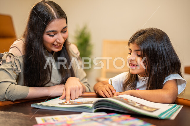 Children learning and development, a Saudi Arabian Gulf mother educating her daughter, helping children in performing homework, educational activities and capacity development, interest in educating children and supporting them