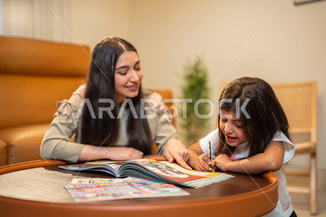 مساعدة الابناء في تأدية الواجبات المدرسية، ام عربية سعودية خليجية تقوم بتعليم ابنتها، الانشطة التعليمية وتنمة القدرات، تعلم وتطوير الابناء، الاهتمام بتعليم بالأبناء ودعمهم