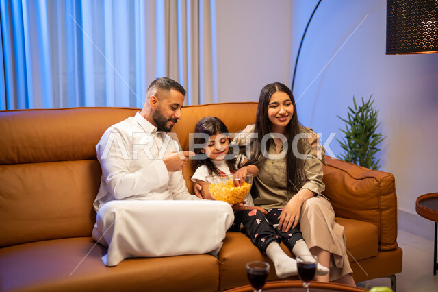 مشاهدة المسلسلات و الافلام, ايماءات تدل على السعادة و الفرح ,الاستمتاع بتناول الفوشار, أجواء عائليه مليئة بالحب, عائلة عربيه سعوديه خليجيه  في غرفة المعيشة, قضاء أوقات ممتعه مع الأبناء