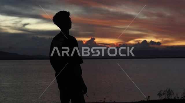 الاسترخاء والتأمل , صورة ظلية من الخلف لشاب يقف أمام بحيرة مائية , السماء والمناظر الطبيعية , منظر غروب الشمس , خلفية الطبيعة , سوليليت .