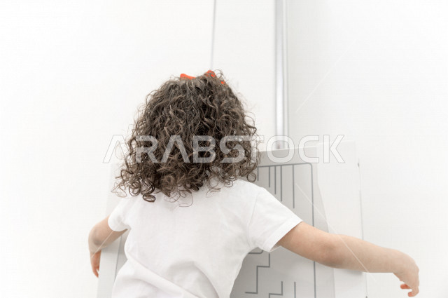 A Saudi Arabian girl stands correctly on a specialized x-ray machine for teeth, dental examination and treatment, a pediatric dental clinic, medical and healthcare concept