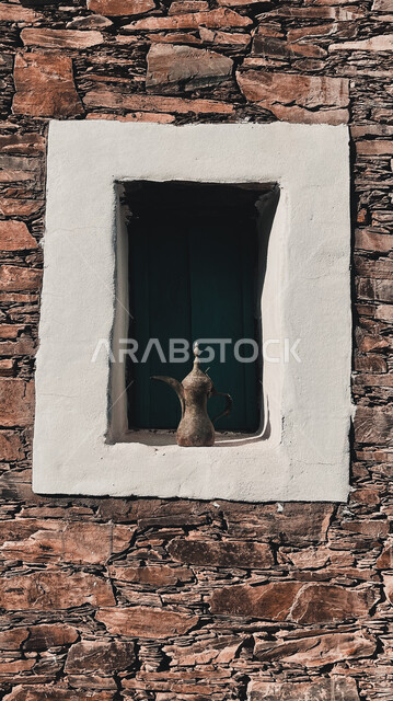  مدينة تاريخية بتصميم معماري عربي وإسلامي قديم, الضيافة عند العرب, دلة قهوة عربية قديمة وسط نافذة في بلد تاريخي في المملكة العربية السعودية , تراثيات سعودية, قطع أنتيكة نحاسية . 