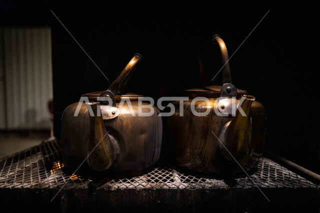 إعداد وتحضير المشروبات الساخنة، صورة مقربة لأباريق الشاي المعدنية العربية الشرقية القديمة على موقد نارالحطب، الاستمتاع بأجواء شتوية دافئة، 
