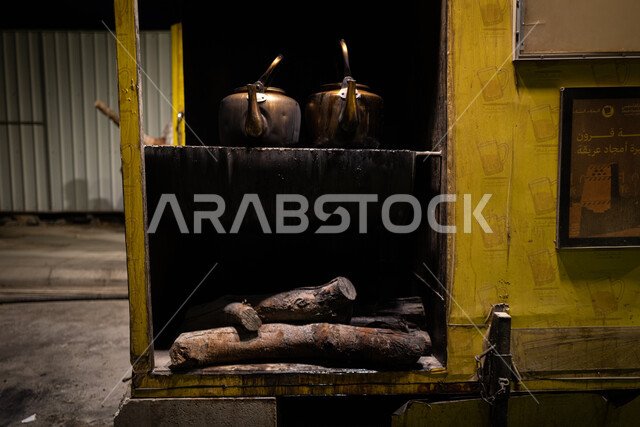 إعداد وتحضير المشروبات الساخنة، صورة مقربة لأباريق الشاي المعدنية العربية الشرقية القديمة على موقد نارالحطب، الاستمتاع بأجواء شتوية دافئة، 