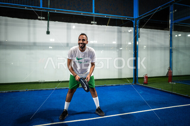 ايماءات تدل على السعادة، أنشطة ترفيهية ورياضات شبابية، اللعب بسرعة وتركيز، مضرب رياضي ، صورة لشاب عربي خليجي سعودي يرتدي الملابس الرياضية يقوم بممارسة كرة التنس في الملعب، نشاط بدني، ملاعب وأندية عامة، الاتحاد السعودي للتنس.