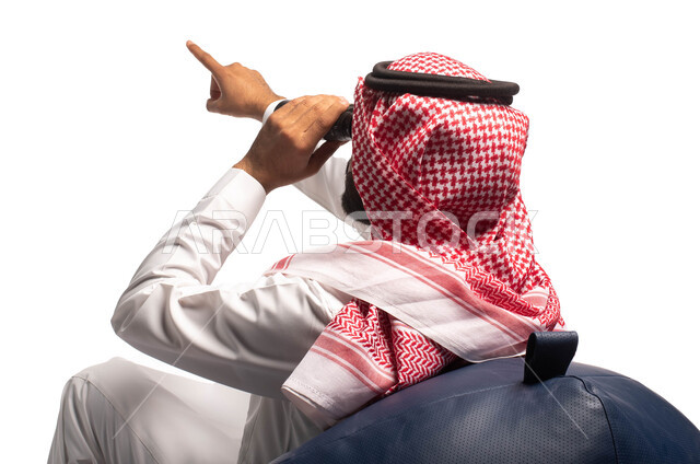 حب الاستكشاف والمغامرة، رؤية الاشياء البعيدة عبر المنظار، بورتريه مقرب لرجل عربي خليجي سعودي يرتدي الزي التقليدي يجلس على كرسي مريح وينظر من خلال منظار الرؤية ويشير بيده لشيء ما, التخطيط المستقبلي للأهداف و الطموحات، خلفية بيضاء