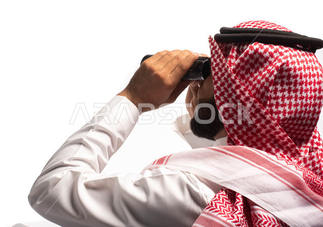 رؤية الاشياء البعيدة عبر المنظار، حب الاستكشاف والمغامرة، بورتريه مقرب لرجل عربي خليجي سعودي يرتدي الزي التقليدي يجلس على كرسي مريح وينظر من خلال منظار الرؤية, التخطيط المستقبلي للأهداف و الطموحات، خلفية بيضاء