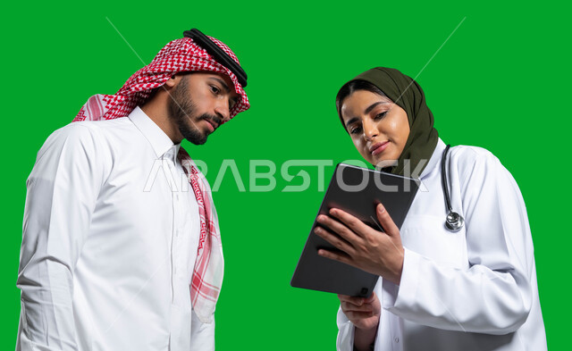 متابعة السجل الطبي الالكتروني الخاص بالمريض, وصف الحالة المرضية وتقديم الاستشارات الطبية، بورتريه مقرب  لطبيبة عربية خليجية سعودية ترتدي المعطف والسماعة الطبية تحمل بيدها التابلت، وصف العلاج لمريض سعودي يرتدي الزي التقليدي، مهن نسائية، كروما، خلفية خضراء.