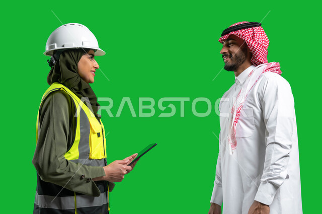 عرض المشاريع و المخططات الهندسية الإلكترونية على جهاز التابلت، وظائف ومهن نسائيه، بورتريه مقرب لمهندسة معمارية عربية خليجية سعودية ترتدي الخوذة وسترة الحماية تتحدث مع رجل عربي خليجي سعودي يرتدي الزي التقليدي, رؤية 2030, كروما، خلفية خضراء.
