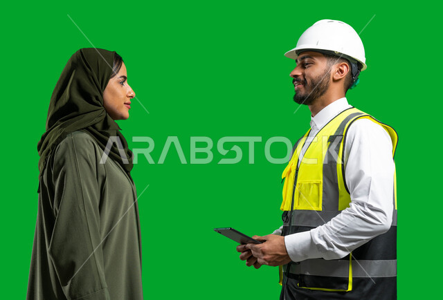   مخططات وتصماميم هندسية إلكترونية, دمج العمل مع التقنية و التكنولوجيا, بورتريه لمهندس عربي خليجي سعودي يرتدي الخوذة وسترة الحماية يحمل بيده جهاز التابلت ويتحدث مع امرأة عربية خليجية سعودية محجبة، مفهوم الهندسة و الإنشاءات المعماريه, كروما, خلفية خضراء. 